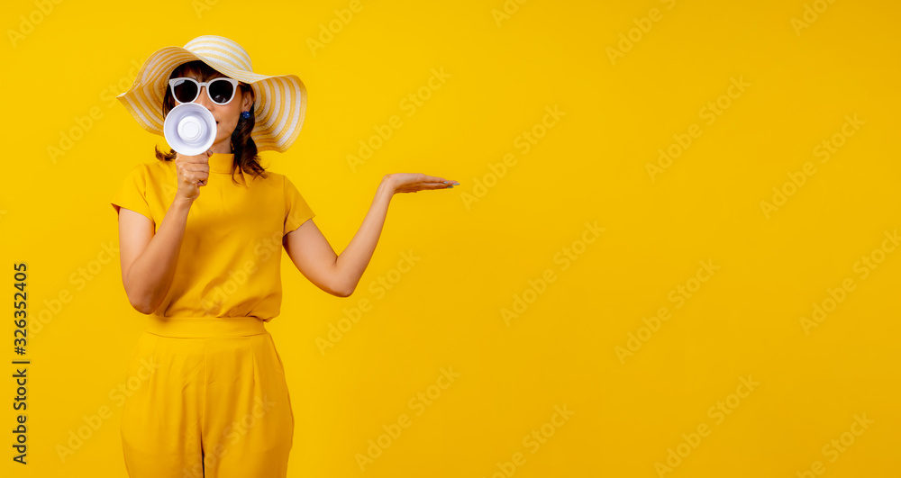 Cute and funny woman in yellow casual cloth style and wearing hat holding white megaphone for announcement and show hand to present product. - obrazy, fototapety, plakaty 