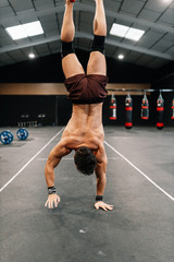 Wall Mural - Young man training on floor in a gym doing handstand walk