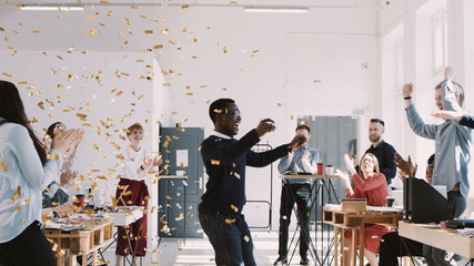 RED EPIC-W Happy young African businessman celebrating success dancing with confetti and team at office slow motion.