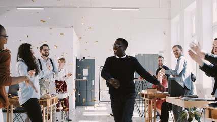 RED EPIC-W Happy young African businessman celebrating success dancing with confetti and team at office slow motion.