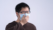 © RomixImage - Young Asian man is coughing, feeling unwell, vomit sick with wearing a medical blue face mask isolated on white background, close up, copy space.