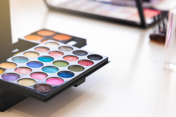 Close up shot of colorful makeup palette on table with light flare effect.