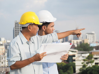 asian male engineer wear safety helmet or foreman and architects Asian people are pointing to Sky train station.