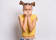 Portrait Of Surprised Or Shocked Teen Girl, On Gray Background. Funny Child Looking At Camera With Hands On Mouth, Biting Nails. Beautiful Caucasian Teenager With Opening Wide Eyes Looking Stressed