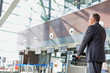 © MDBPIXS - Mature businessman pushing baggage cart for check in at airport
