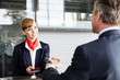 © MDBPIXS - Passenger service agent giving businessman passport and boarding pass in check in area at airport