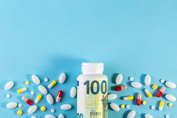 Money and pills of different colors on blue background. Rising cost of health care. Rising cost of health care. copy space. Pharmaceutical medicament, cure in container for health. Medicine concept.