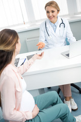 Wall Mural - happy pregnant woman having consultation with doctor in gynecological clinic