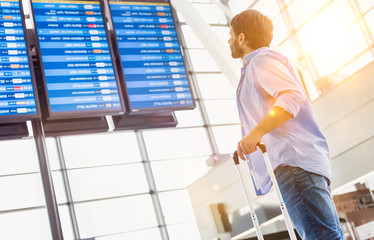 Wall Mural - Low angle view of man looking at his flight on screen in airport