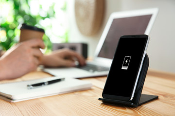Man working at table while his mobile phone charging with wireless device