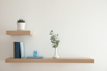 Wooden Shelves With Beautiful Plants, Alarm Clock And Books On Light Wall