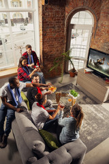 Wall Mural - Excited group of people watching american football, sport match at home. Multiethnic group of emotional friend, fans cheering for favourite national team, drinking beer. Concept of emotions, support.