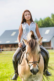 Portrait of young attractive woman riding horse in ranch
