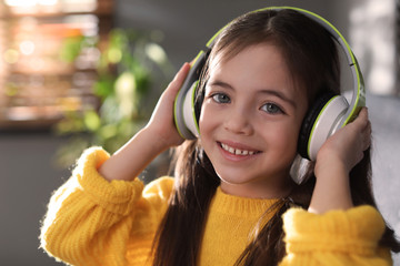 Sticker - Cute little girl with headphones listening to audiobook at home