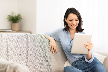 Young woman using digital tablet sitting on couch