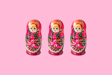 Three Russian dolls matryoshka isolated on pink background. Creative layout with traditional Moscow toys