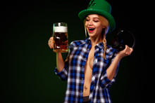 Saint Patrick Day. Young Sexy Oktoberfest Girl Waitress In Green Har Serving Big Beer Mugs With Beer Isolated On Dark Background. St Patricks Day Celebration.