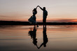 © malysheva - Young couple dancing in the water on Sunset. Two silhouettes against the sun. Romantic love story.