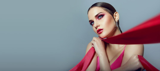 Portrait of a beautiful young girl with bright pink make-up and with pink ribbons in her hands.