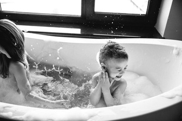 Black and white photo of children taking a bath with splashing water.