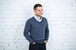 © DSMT - young guy in a shirt and sweater against a white brick wall