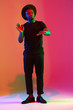 © master1305 - Young african-american musician singing on gradient orange-purple studio background in neon light. Concept of music, hobby, festival. Joyful party host, stand upper. Colorful portrait of artist.