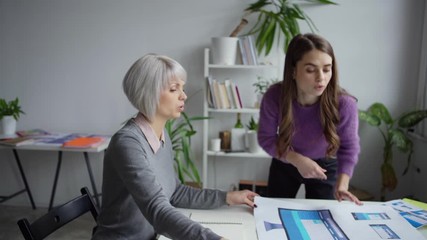 Wall Mural - young female web designer putting on table blueprint with website design for different devices and d