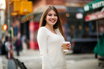 Wall Mural - Beautiful woman with natural smile enjoy her day in the city drinking coffee outdoors