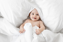 Smiling Baby Peeking From White Sheets
