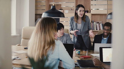 Sticker - Emotional Caucasian female CEO guides colleagues at multiethnic business team meeting in modern stylish office space 4K.