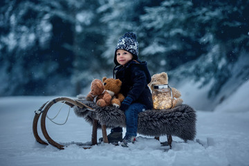 Poster - Cute boy playing with teddy bear in the snow, winter time. Little toddler playing with toys on a snowy day