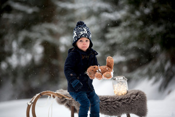 Canvas Print - Cute boy playing with teddy bear in the snow, winter time. Little toddler playing with toys on snowy day