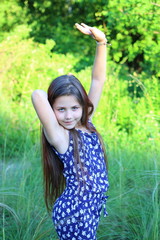  Cute Caucasian girl in a blue romper walks on a green lawn in a park. The concept of summer and relaxation. Vacations and leisure for children. Nature and flowers.