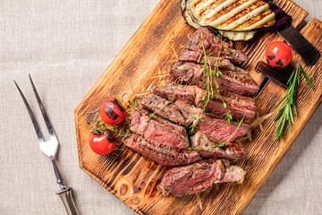 Wall Mural - Juicy medium rare beef steak slices on wooden board with herbs spices and salt.