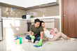 © makistock - Young happy Asian couple is having fun while doing cleaning at home.