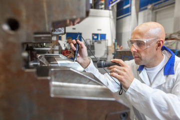 Engineer doing maintenance on a injection mold for plastic components, industrial and automotive concept