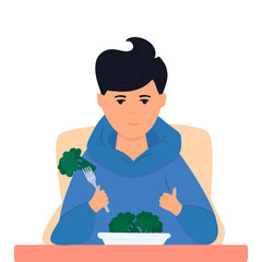 Healthy food concept. Teenager boy eats vegetables with pleasure. Vegetarian guy holds broccoli on a fork. Like hand gesture