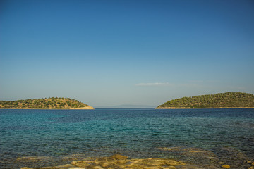 idyllic peaceful two island coast line picturesque landscape scenic view Aegean sea Eastern Greece waterfront district area cozy lagoon waters foreground and clear sky background space