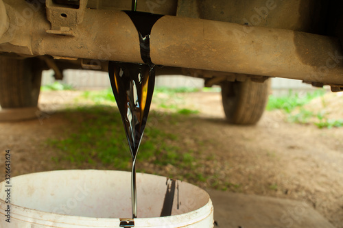 Cuadros en Lienzo Old car oil is poured into a bucket. Changing the oil in the car.