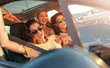 Three female friends enjoying road trip traveling at vacation in the car.