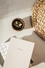 Wall Mural - Notebooks, clips in wooden bowl, straw stand on beige concrete background. Flat lay, top view.