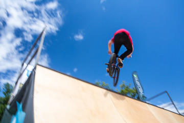  Bmx rider jumping over on a U ramp in a skatepark (motion blurred image)