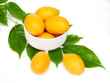 Sweet yellow marian plum fruit, maprang or mayongchid in bowl with green leaves isolated on white background.