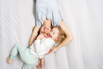 family time: mom and daughter are lying on the bed hugging and laughing merrily.
