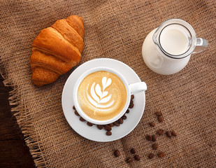 Wall Mural - white cup of coffee on burlap carafe of milk grain