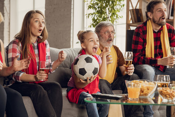 Wall Mural - Excited, happy big family watching football, soccer match on the couch at home. Fans emotional cheering for favourite national team. Having fun from grandparent to children. Sport, TV, championship.