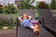 © Maria - A cute little girl relaxing on the chaise longue at green garden outside, home feeling