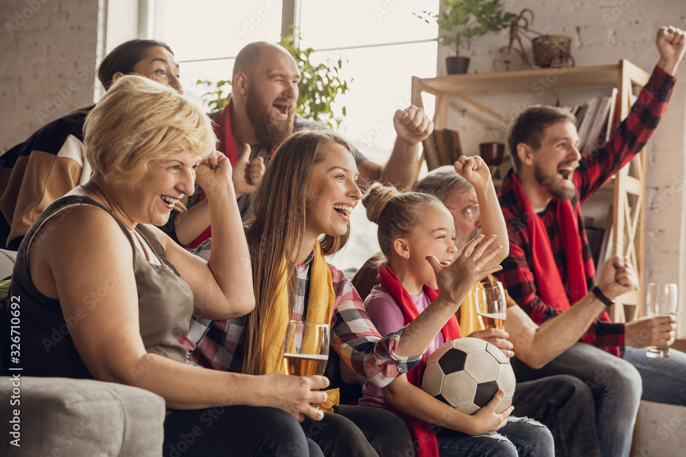 Excited, happy big family watching football, soccer match on the couch ...
