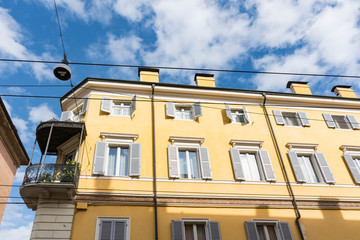 Yellow orange building with balcony and shutters. Modena, Italy