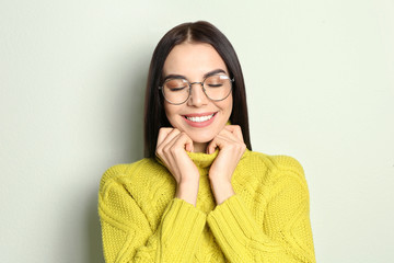 Poster - Young woman wearing warm sweater on light background. Winter season